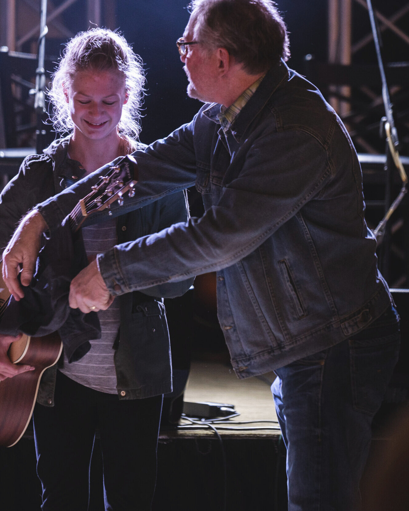 Scott handing a new acoustic guitar to a young woman on stage
